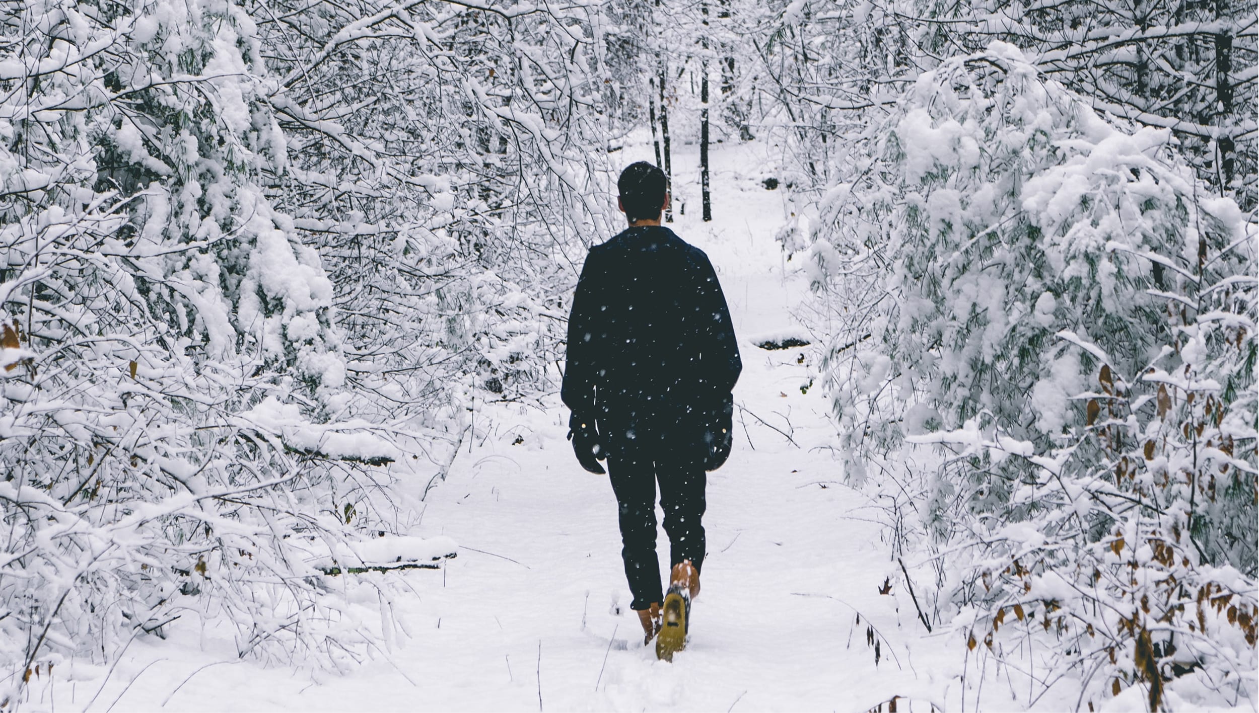 Lone figure of a man walking on a snowy path