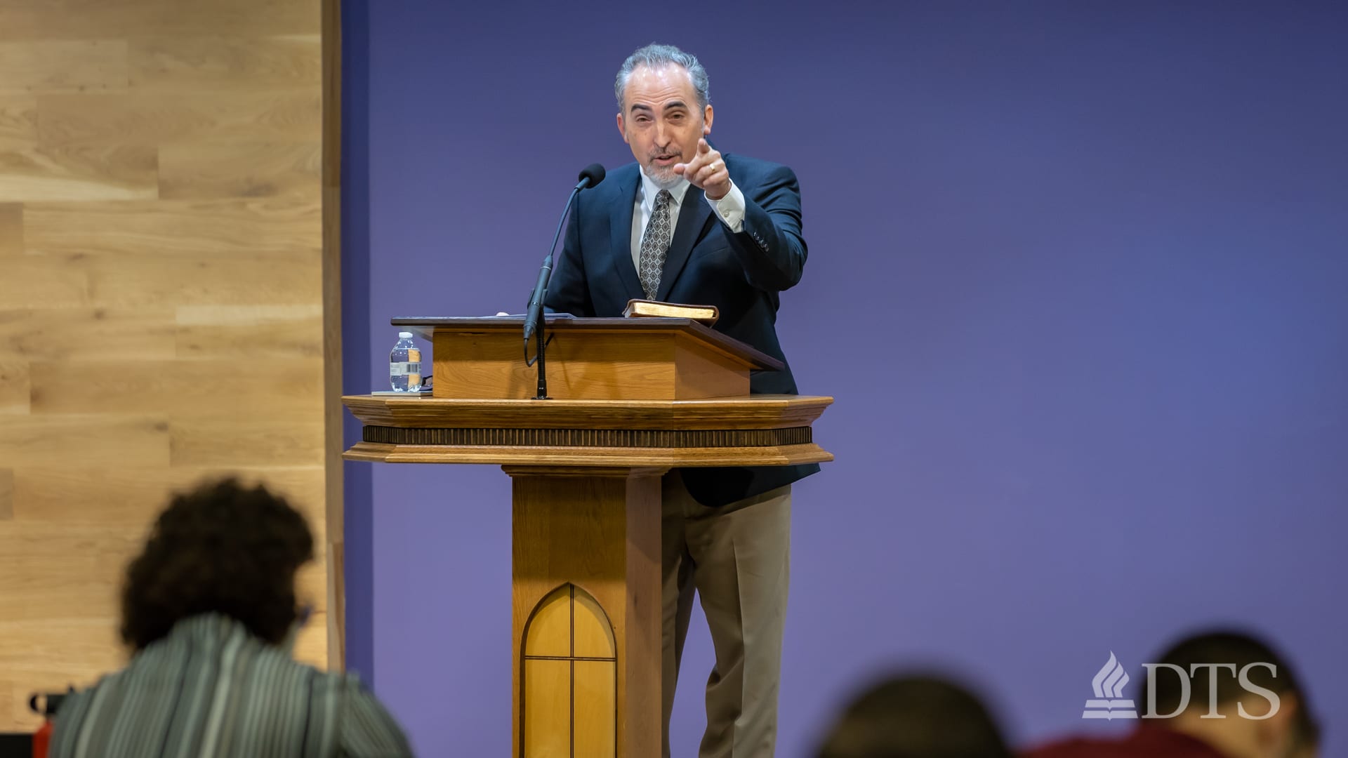 Dr. Mark Yarbrough pointing toward his audience while standing at a podium speaking into a microphone