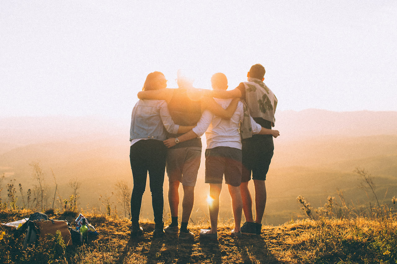 four friends outdoors facing the sunset