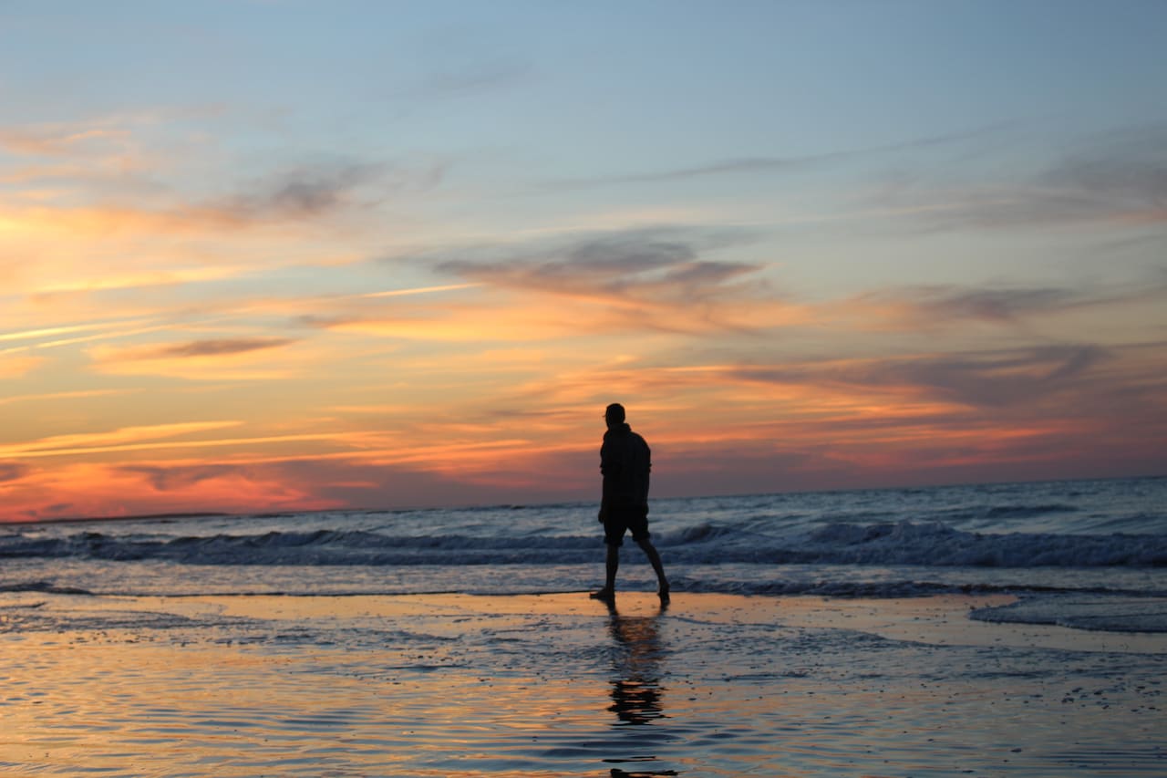 Man walking on the beach during sunset