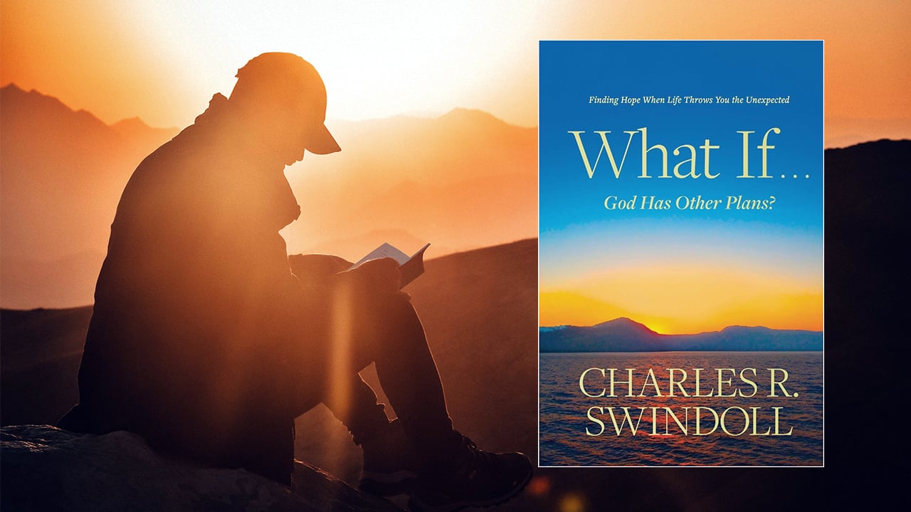 Man seated outside reading a book by Dr. Swindoll