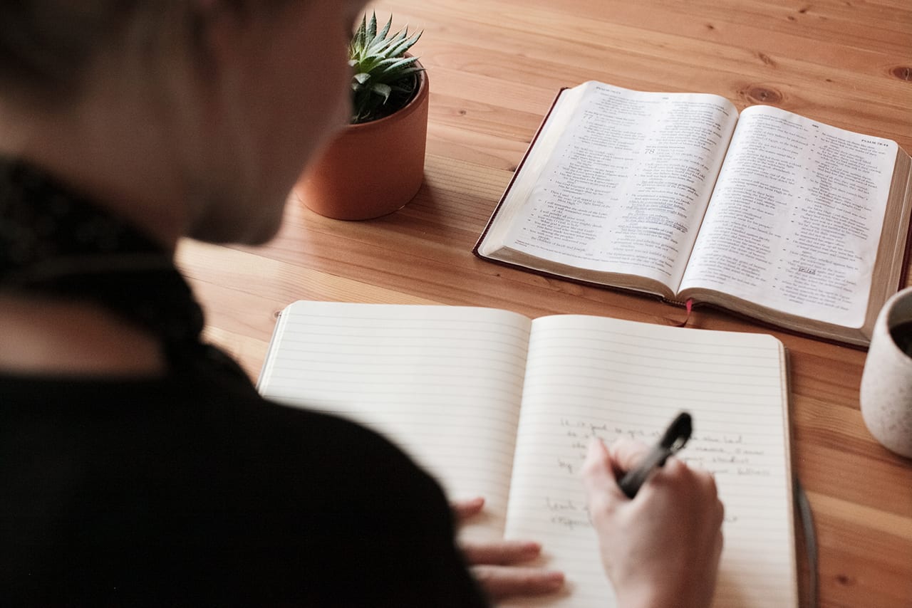 Woman taking notes while reading her Bible