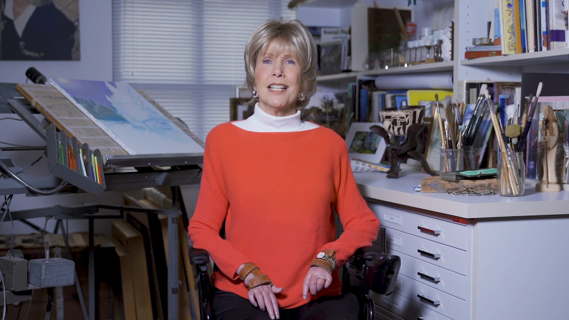 Joni Eareckson Tada seated in her art studio looking at the camera
