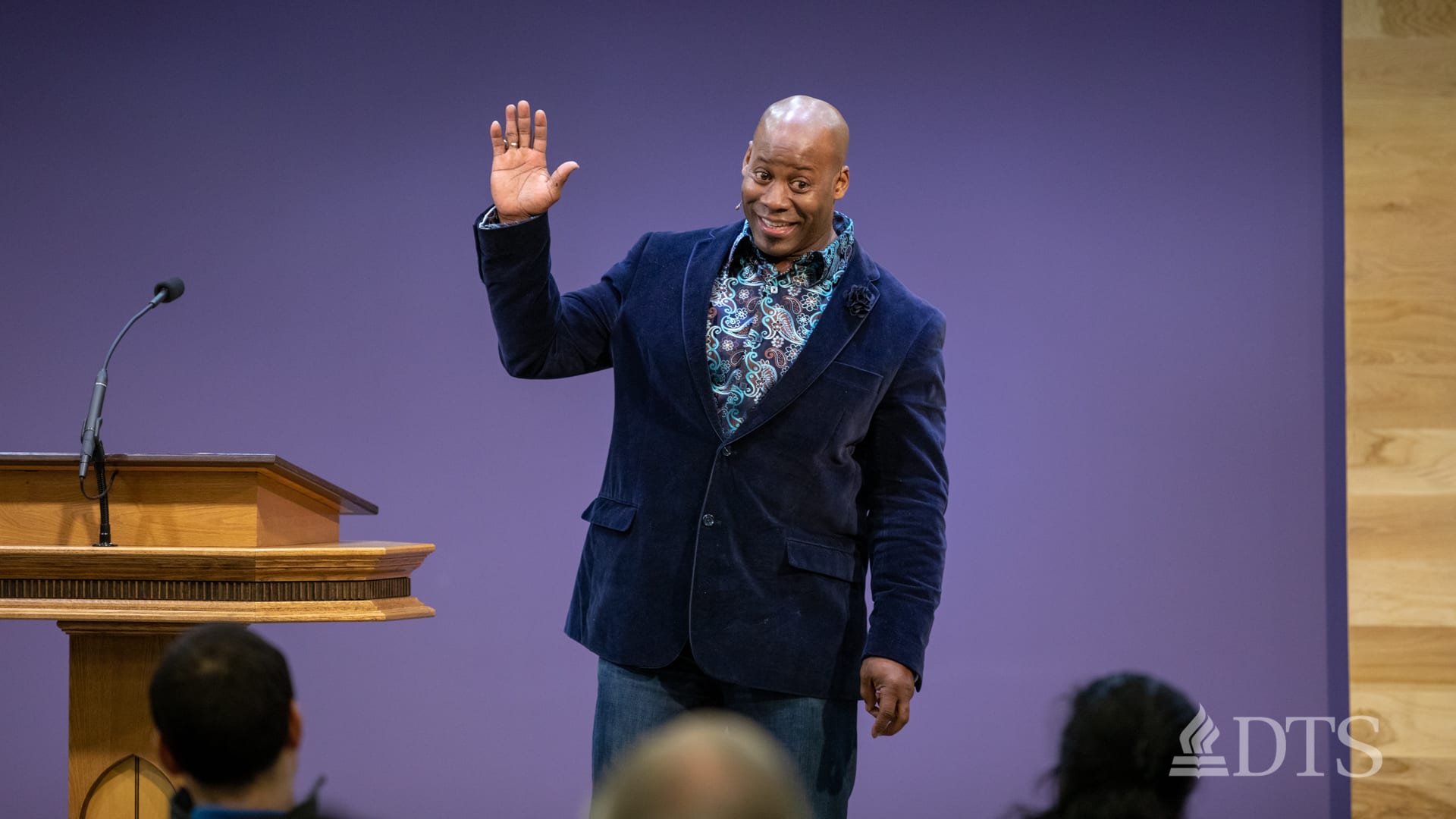 man standing near podium with hand raised speaking at DTS Chapel