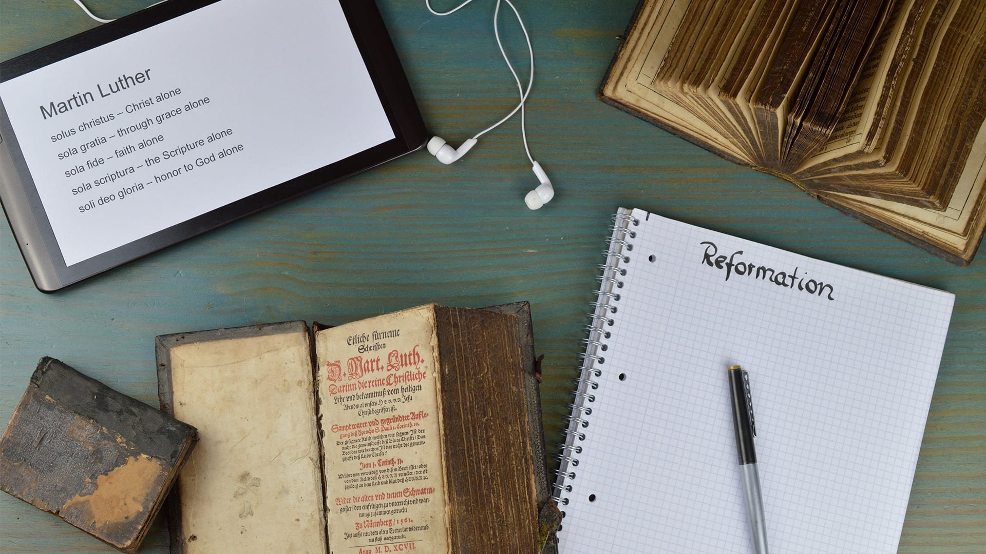 Desktop with books related to the Reformation with headphones and paper
