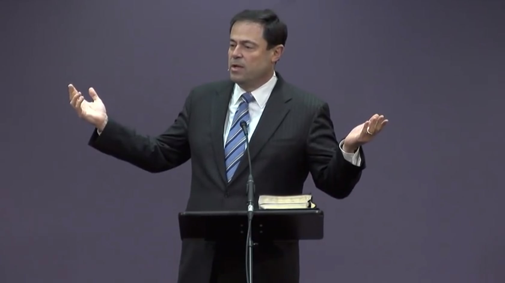Dr. Mark Dever standing with arms outstretched speaking at a podium