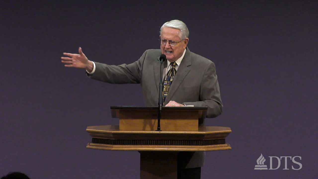 Dr. Chuck Swindoll standing at podium with arm outstretched while speaking at DTS Chapel