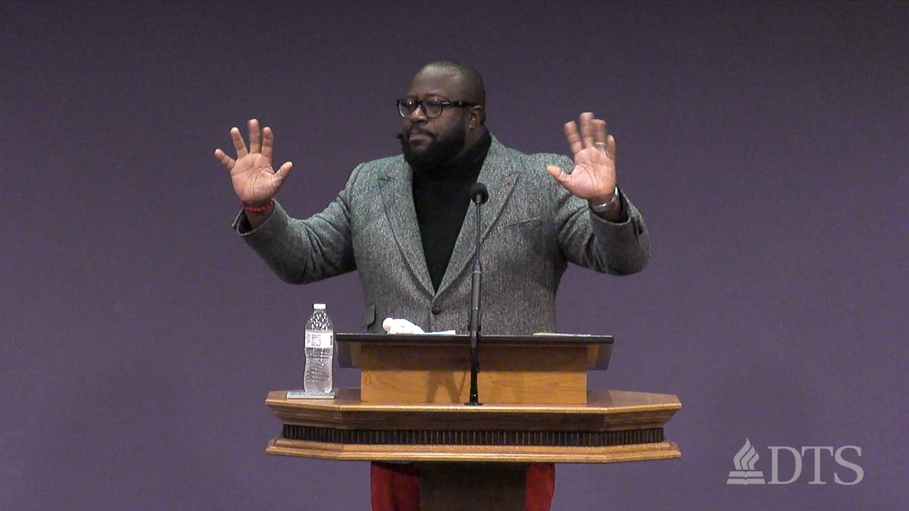 man standing at podium with arms outstretched while speaking at DTS Chapel