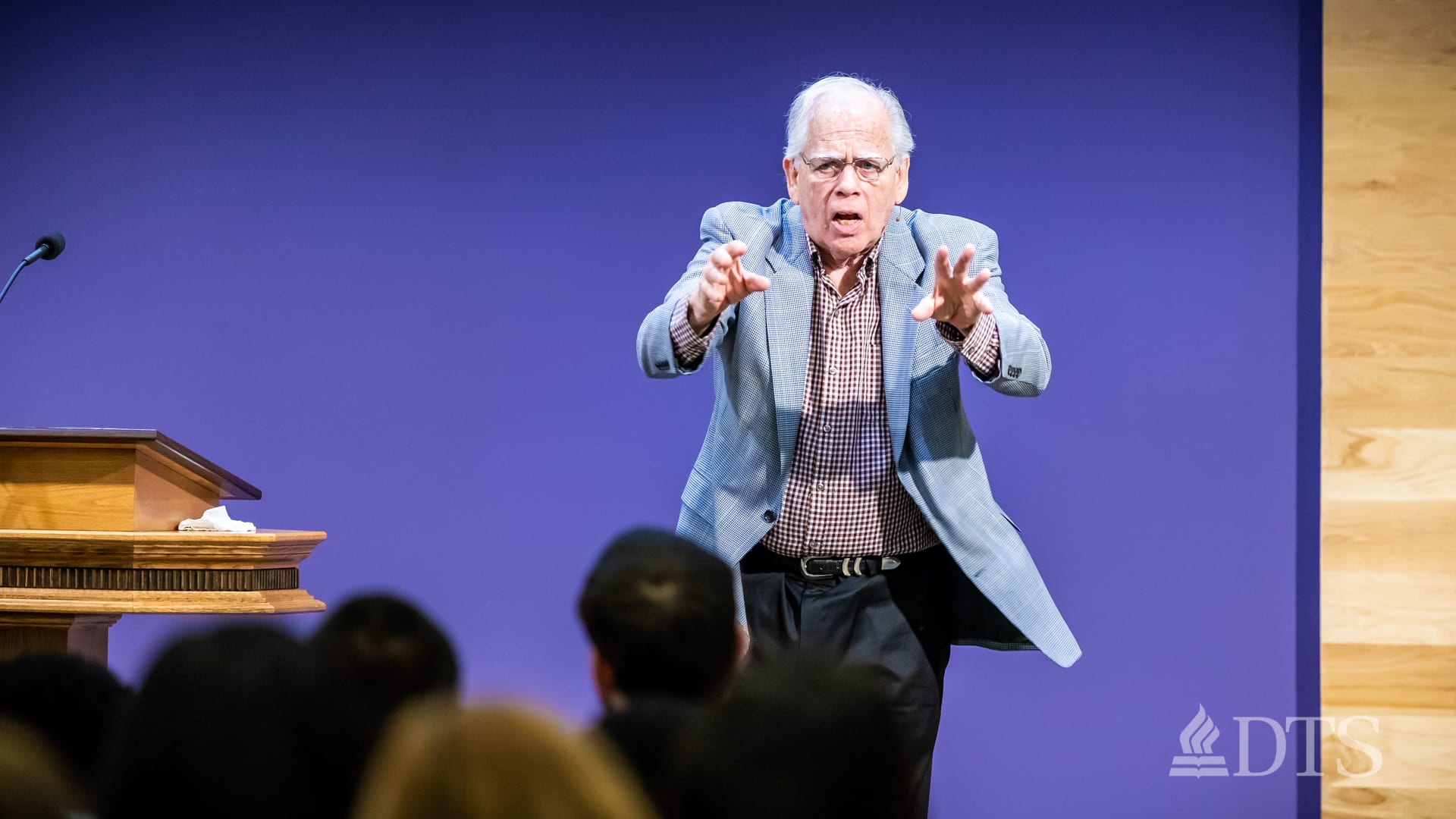 man standing near podium with arms outstretched while speaking at DTS Chapel
