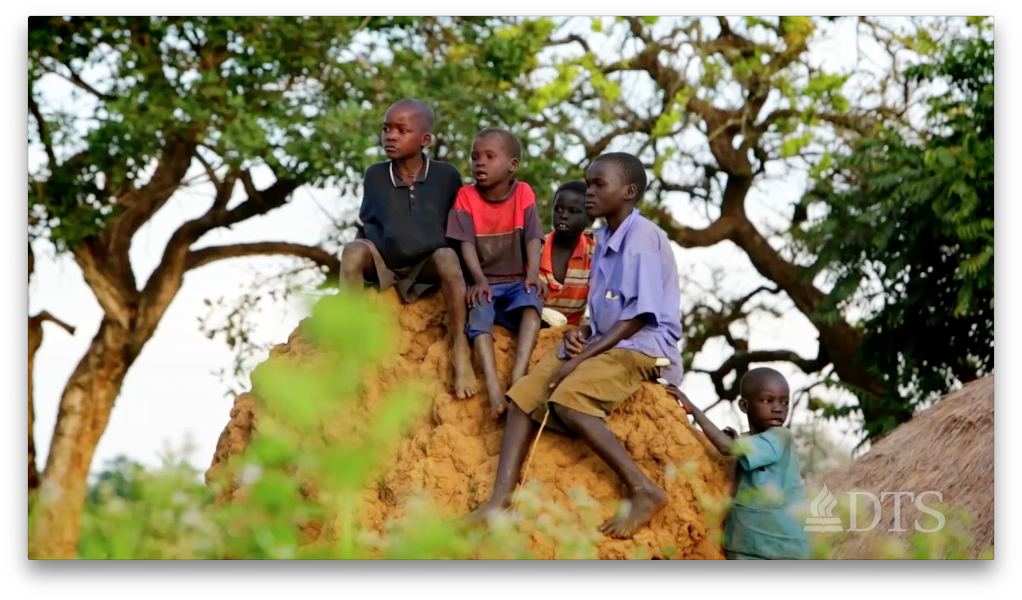 Five young children climbing a mound of dirt