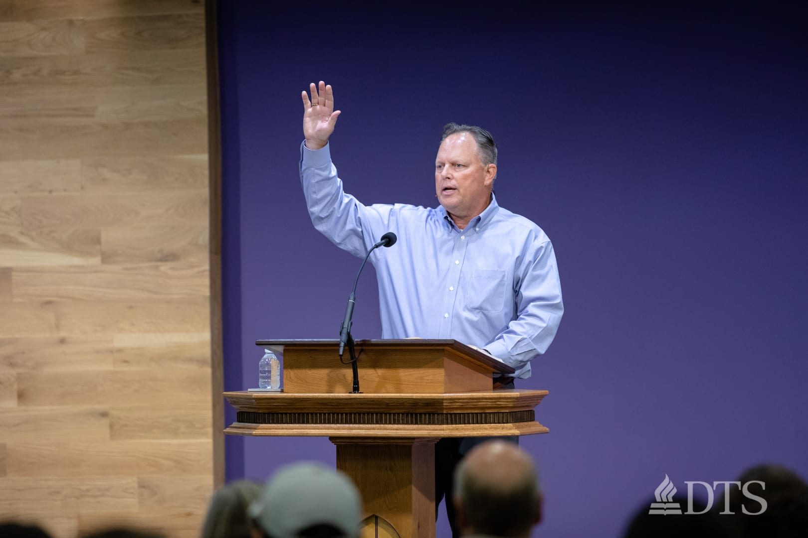 man standing at podium with hand raised while speaking at DTS Chapel