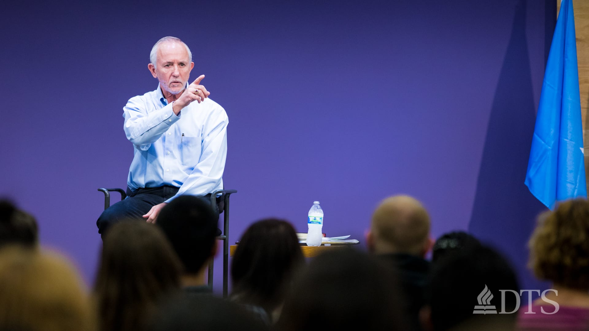 man seated on stage speaking at DTS WEC Week