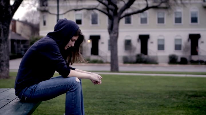 woman sits on picnic bench in park