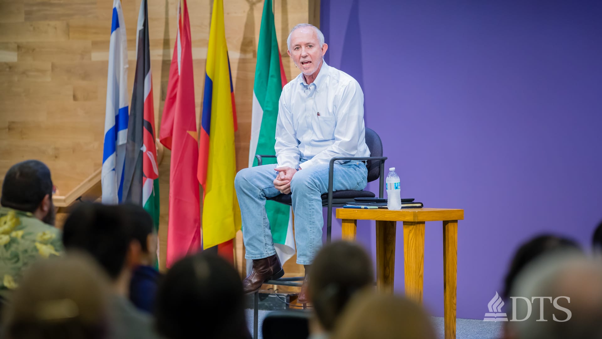 man seated on stage speaking at DTS WEC Week