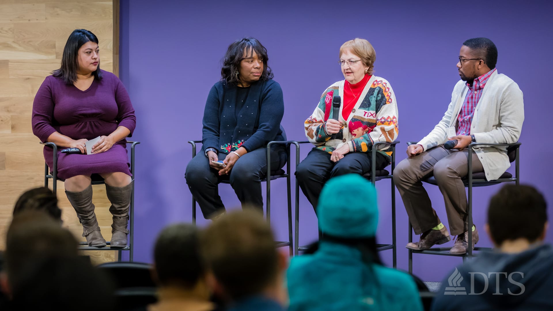 man and women seated in stools on stage during panel discussion in DTS Chapel