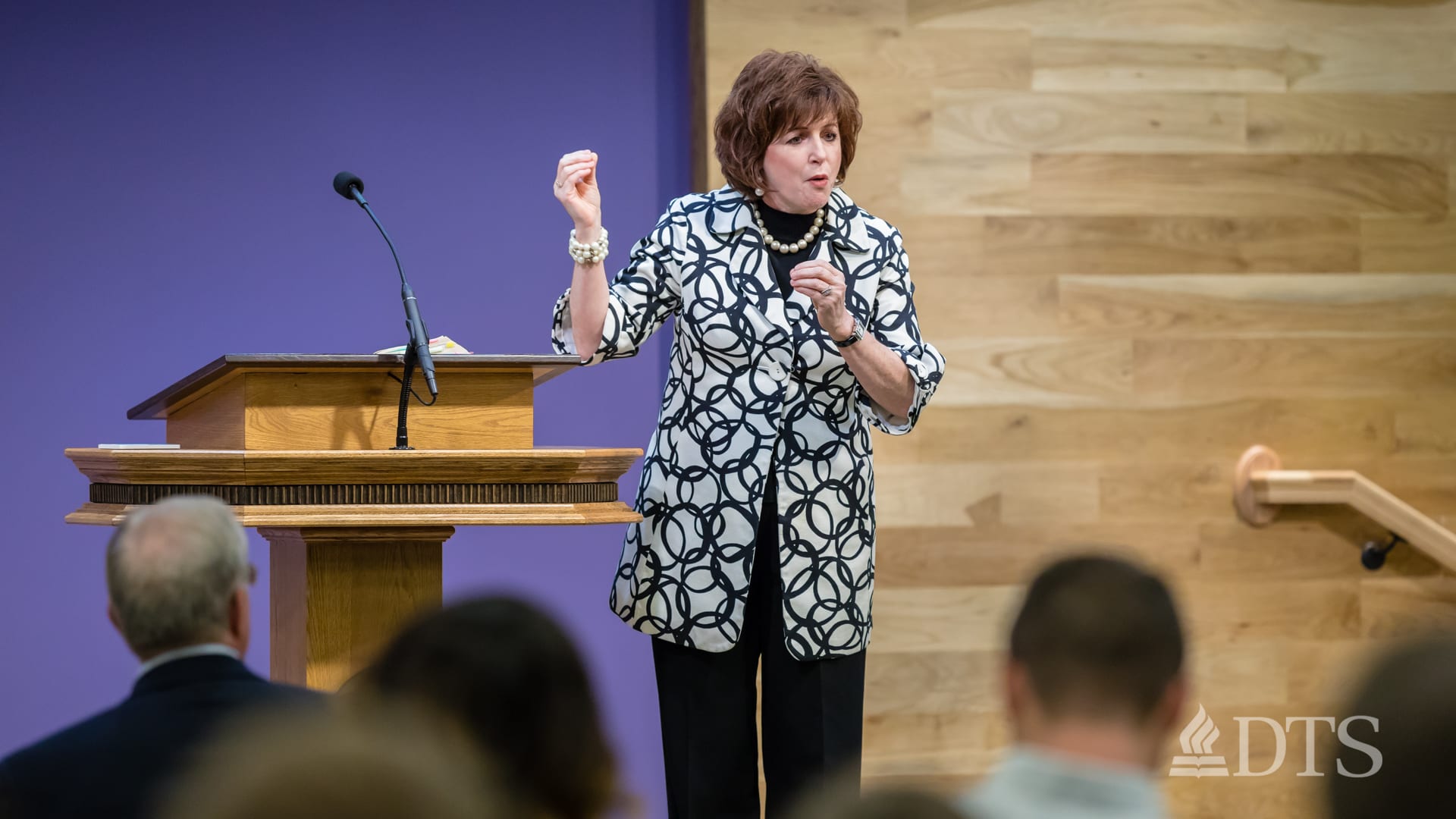 woman standing near podium speaking at DTS Chapel