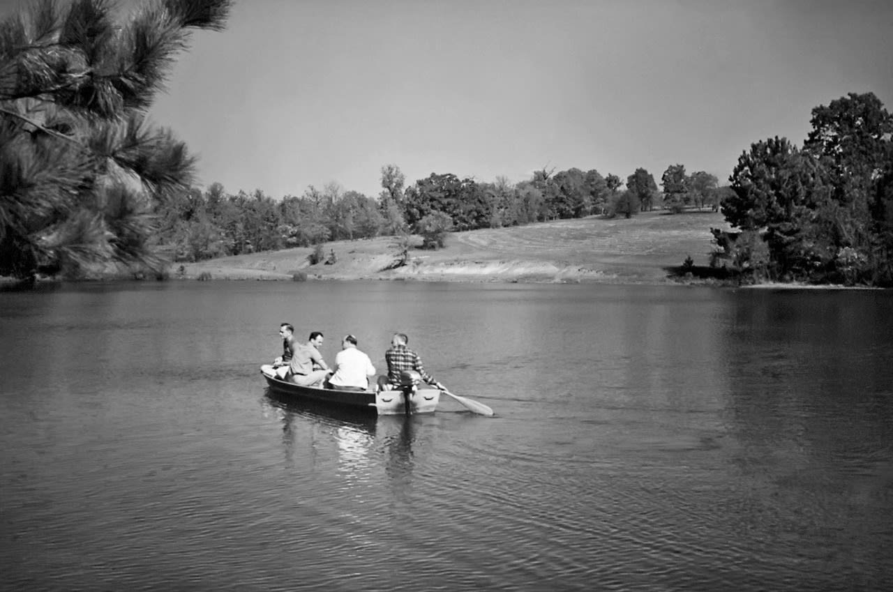 Four men in a boat rowing in still water