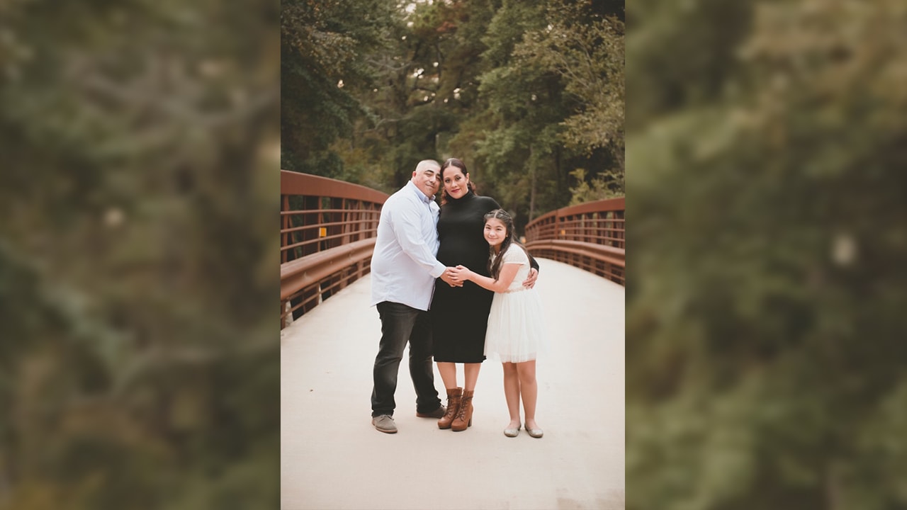 Eduardo Perez standing on bridge with wife and young daughter