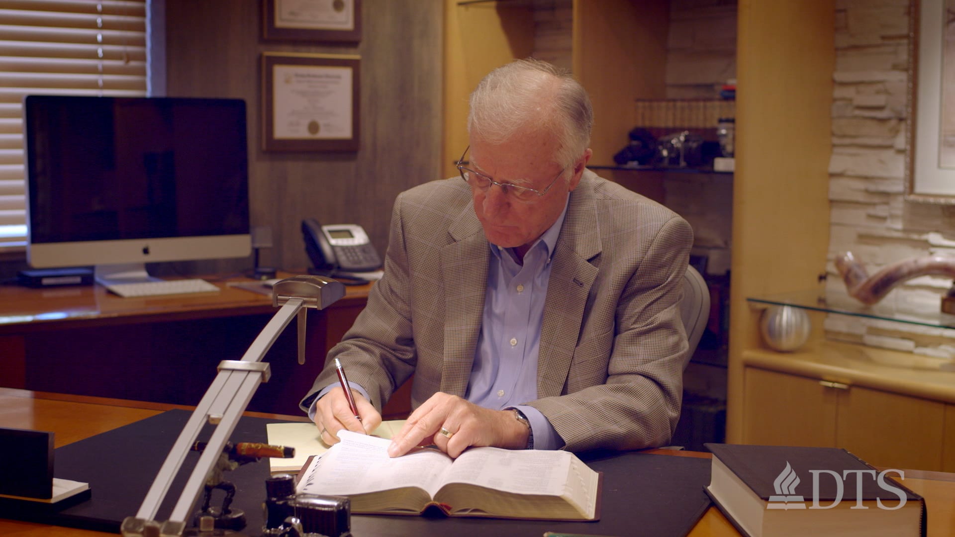 Dr. Lutzer seated at his desk studying the Bible