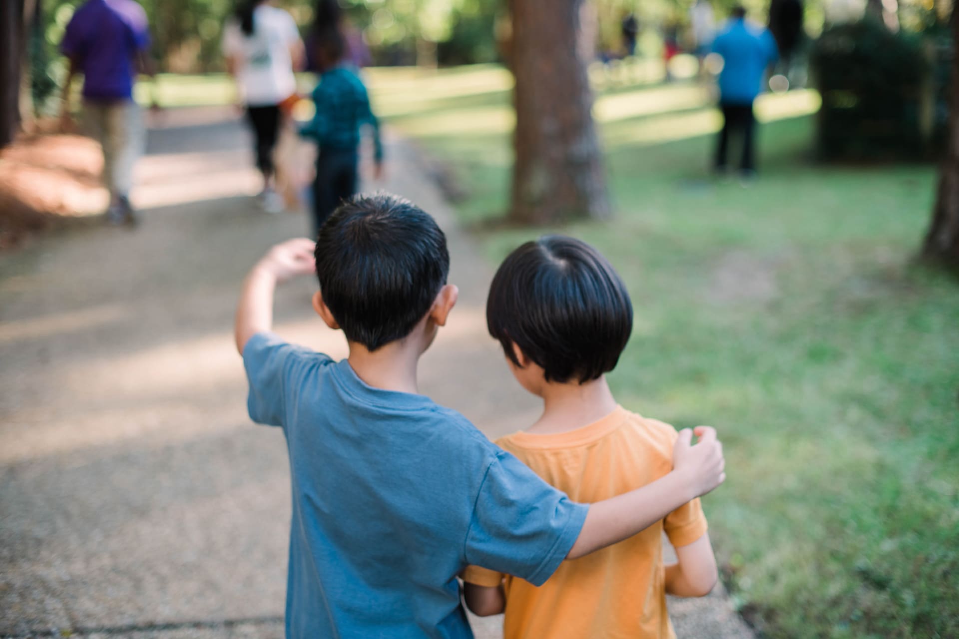 Young children talking while people walk in a park