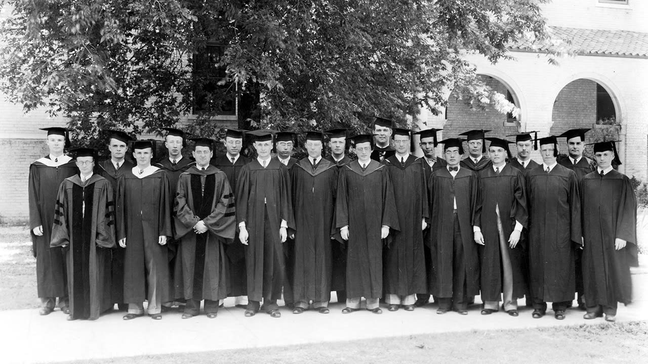 Group of male graduates in caps and gowns on DTS campus