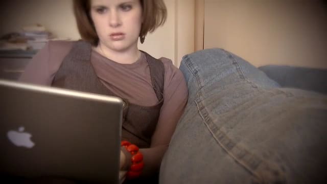 woman reclines on couch while using laptop