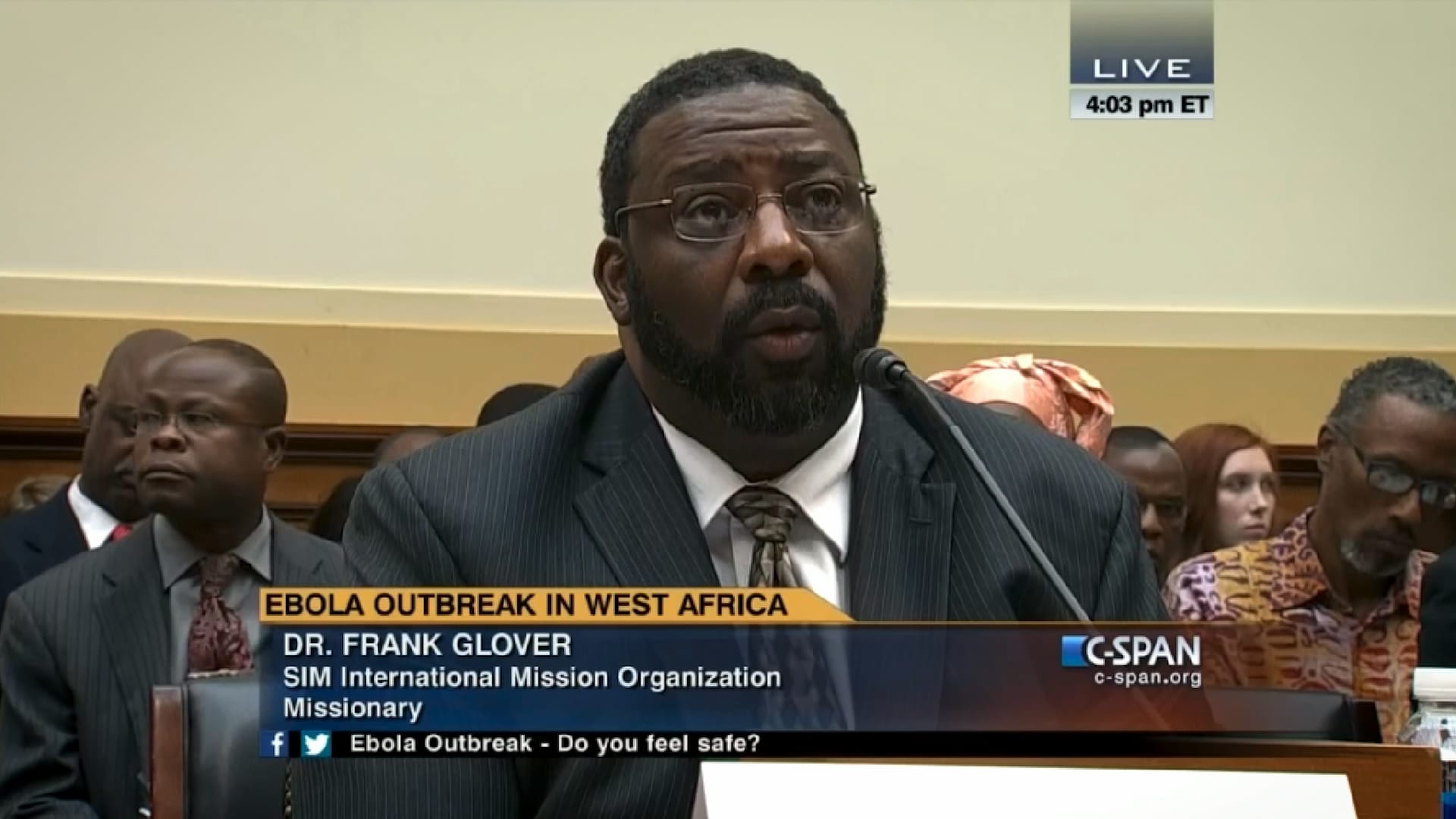 Dr. Frank Glover speaking into a microphone during a hearing