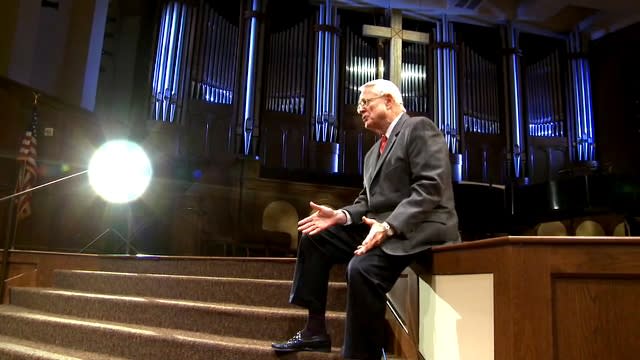 Dr. Chuck Swindoll seated by stairs inside his church's sanctuary