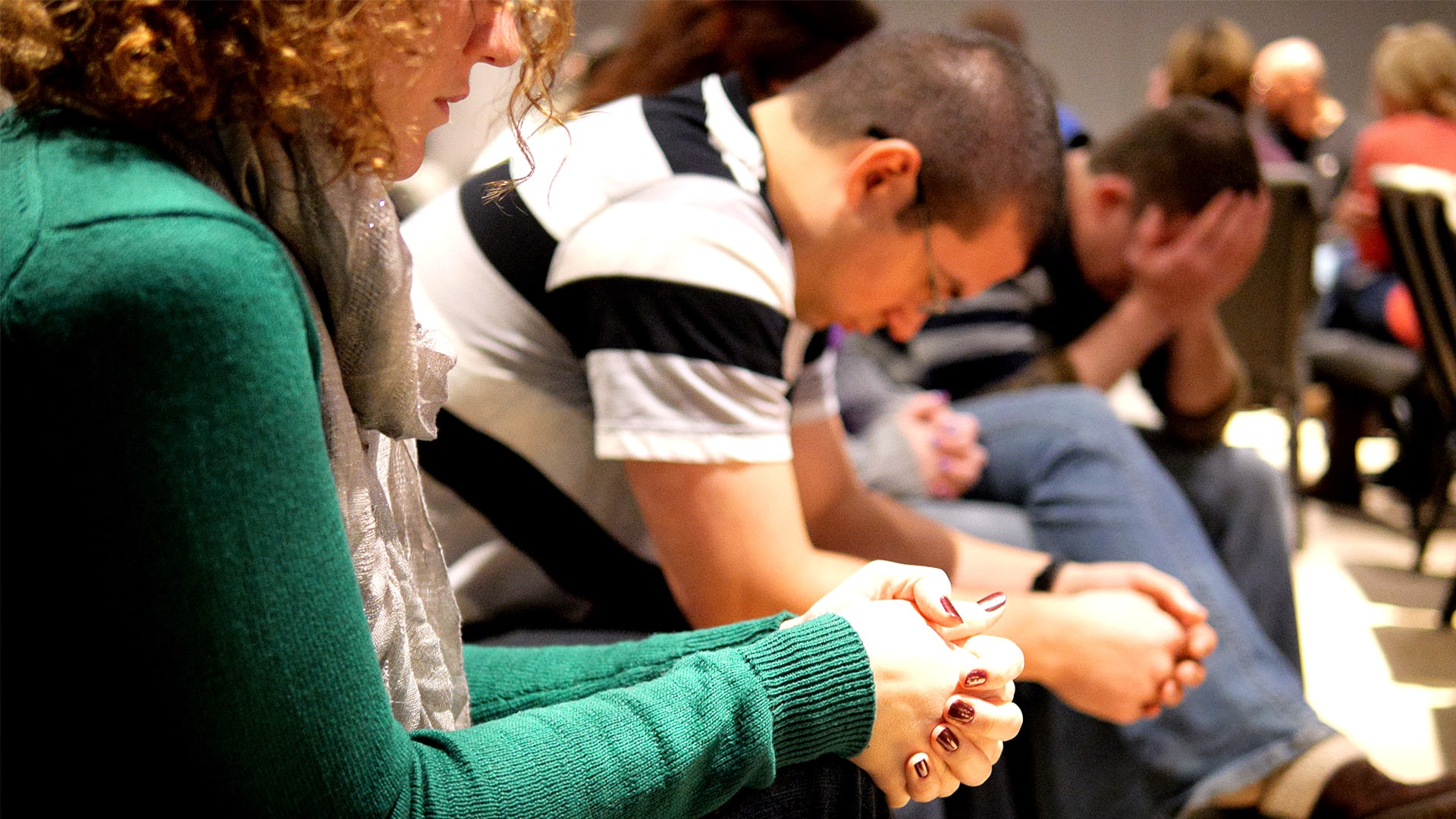 men and woman bowing heads in prayer