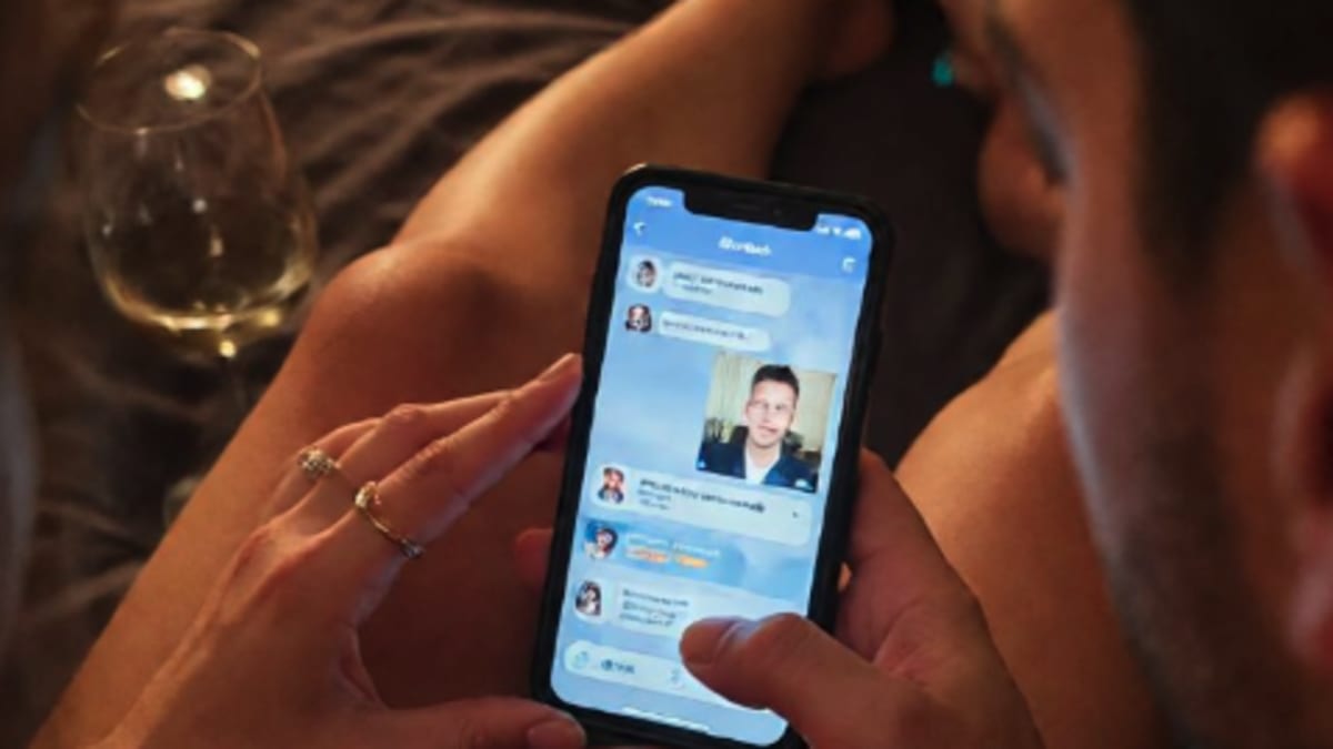 Manos de una pareja compartiendo un teléfono móvil sobre la cama, eligiendo juntos entre perfiles de chat