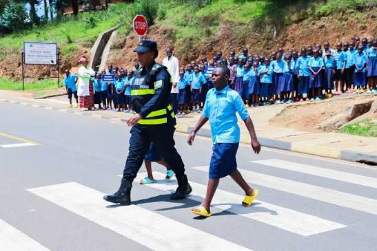 Askari wa usalama barabarani akisaidia watoto wa shule kuvuka barabara salama