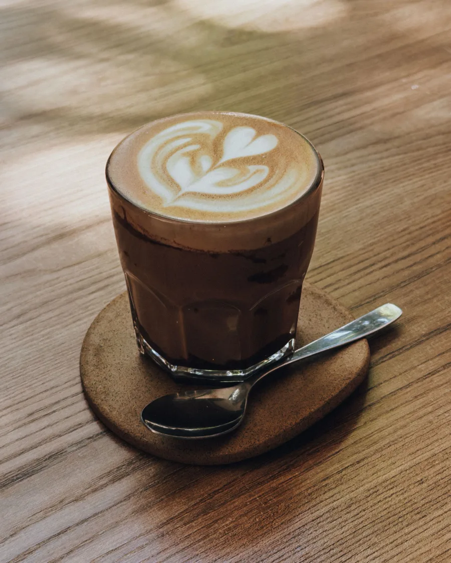 Close-up of a caffè latte in a glass with latte art and a spoon