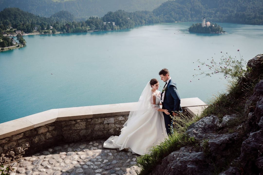 Wide couple portrait on Bled Castle terrace overlooking Lake Bled.
