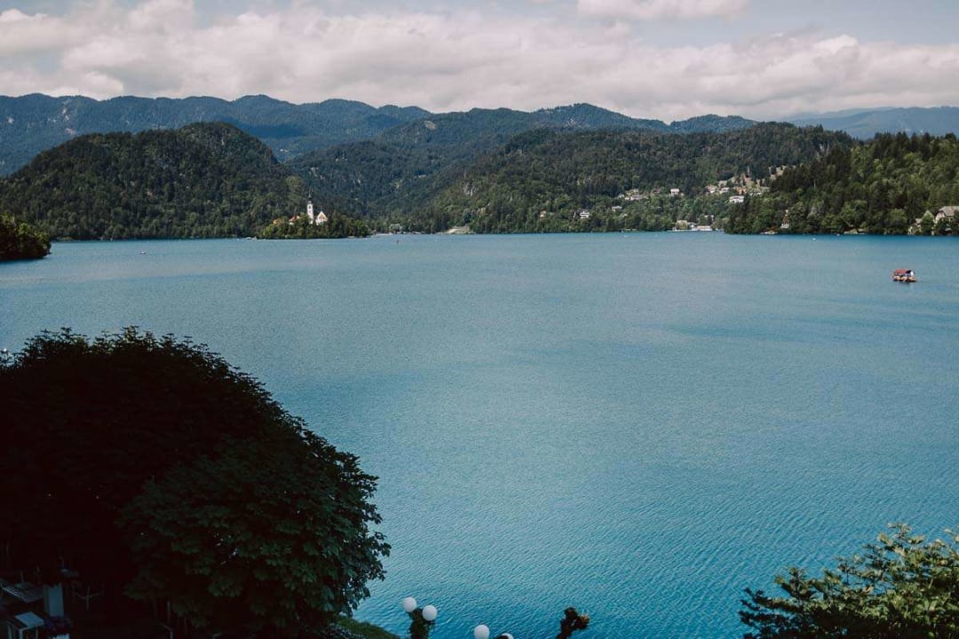 A scenic view of Lake Bled with its turquoise waters, lush green mountains, and the iconic church on the island in the distance.