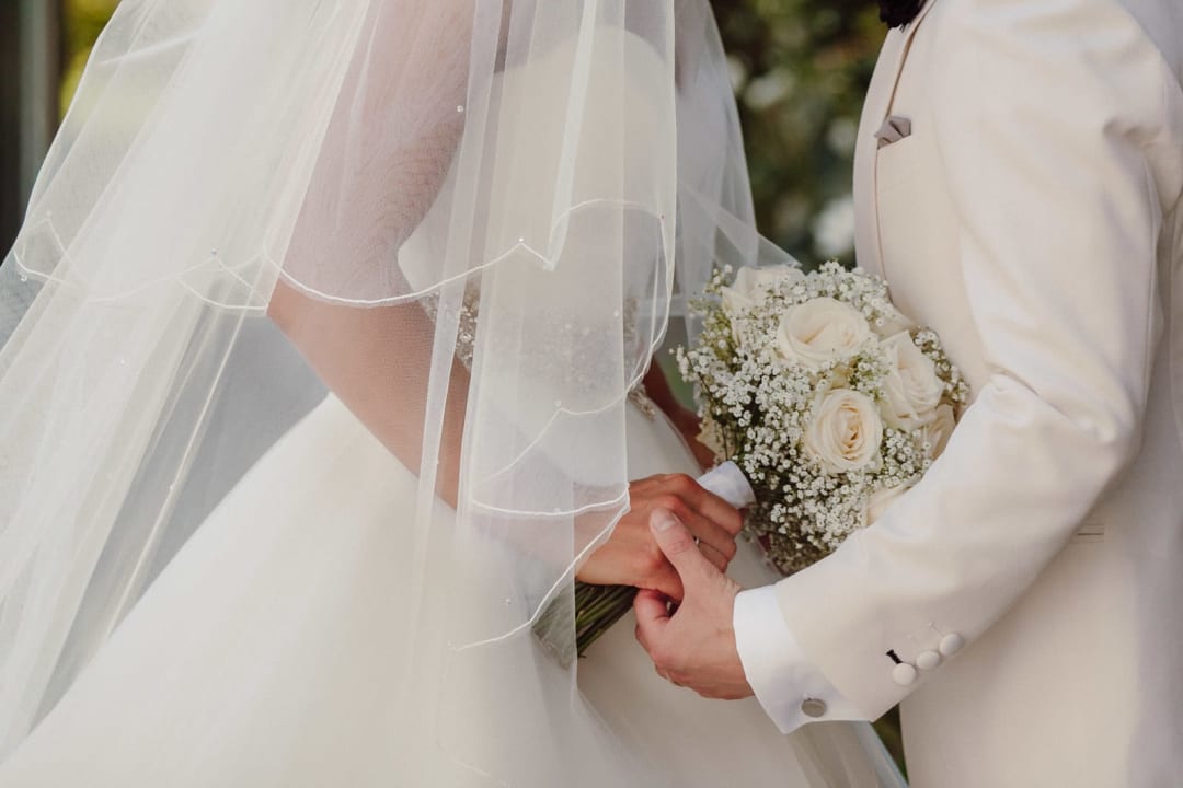 Close-up of veil and bouquet with hands, soft editorial detail.