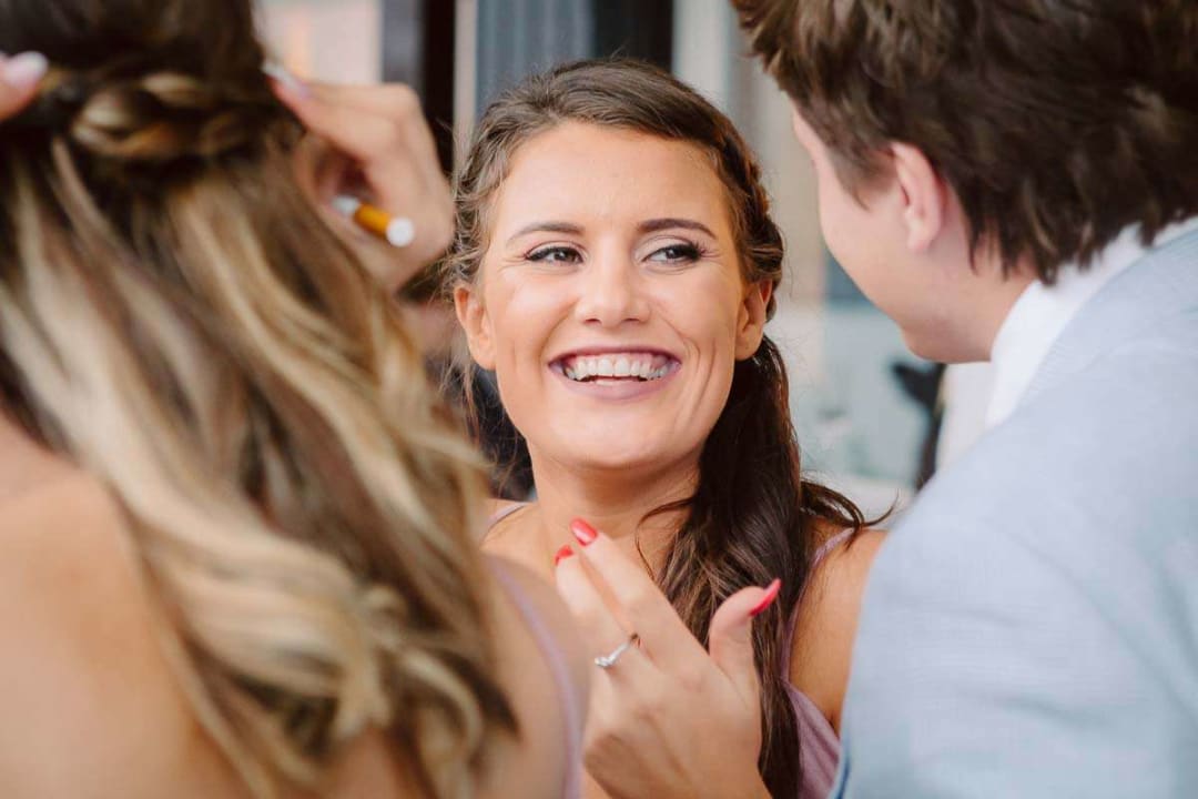 A wedding guest with braided hair laughing and engaging with others during a celebration.