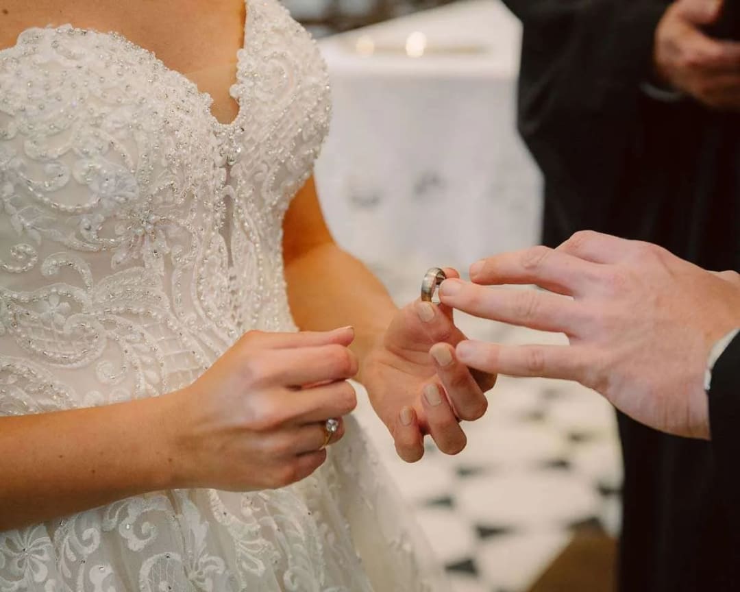 A close-up of a bride and groom exchanging rings during their wedding ceremony.