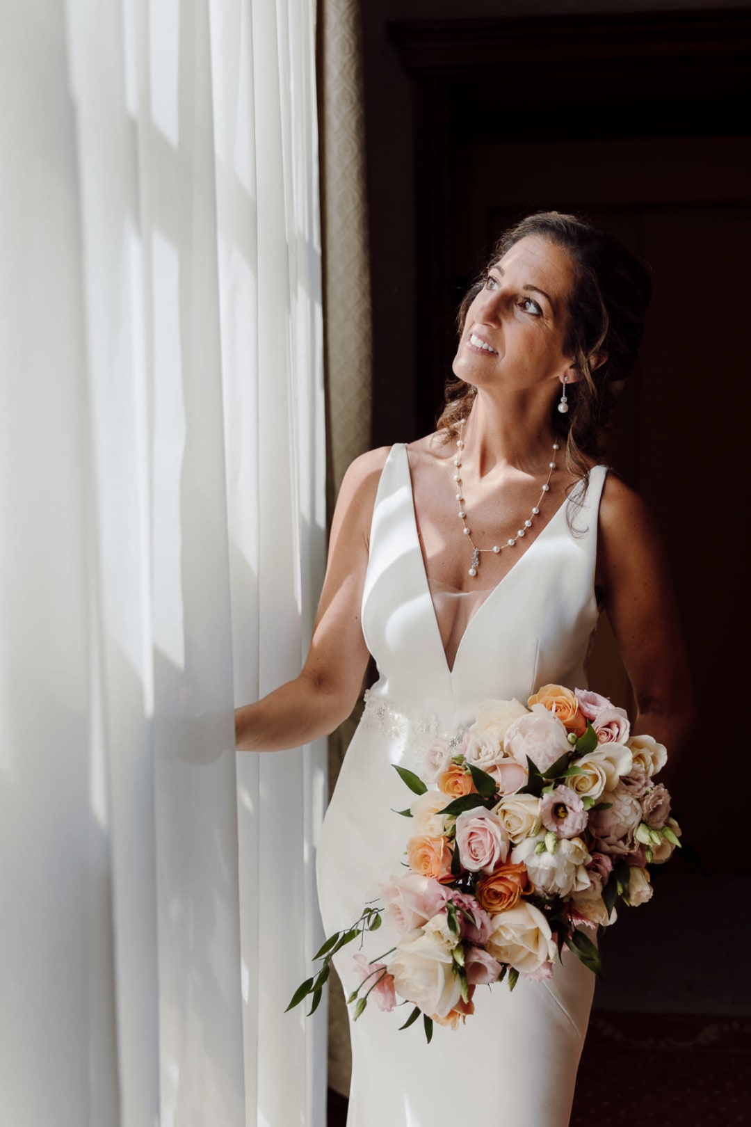 Bride holding her bouquet by the window before the ceremony.