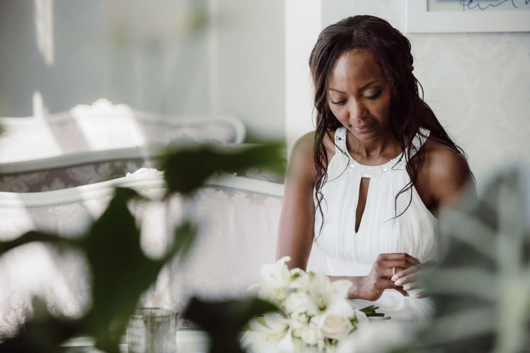 Quiet bridal prep moment with soft foreground blur and gentle window light.