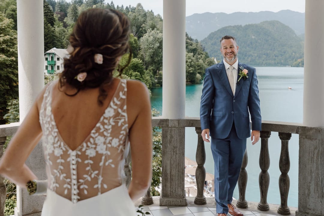 Groom seeing the bride for the first time on a balcony overlooking Lake Bled.