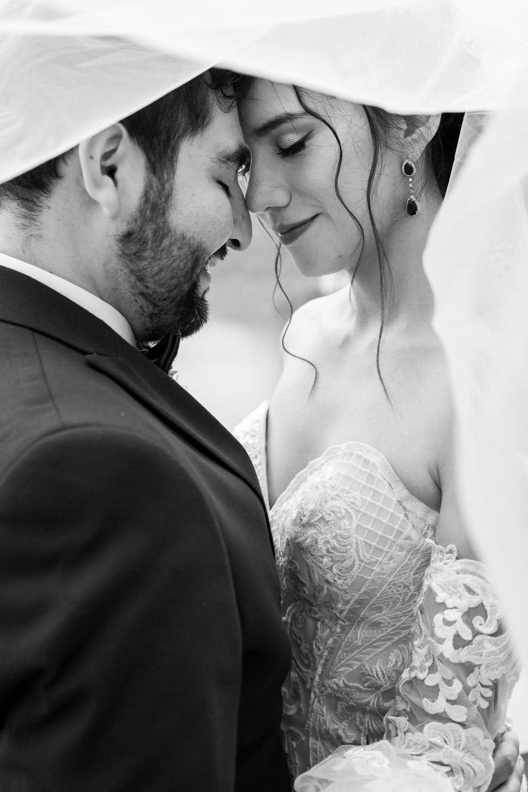 Intimate couple portrait under the veil, black-and-white and emotional.