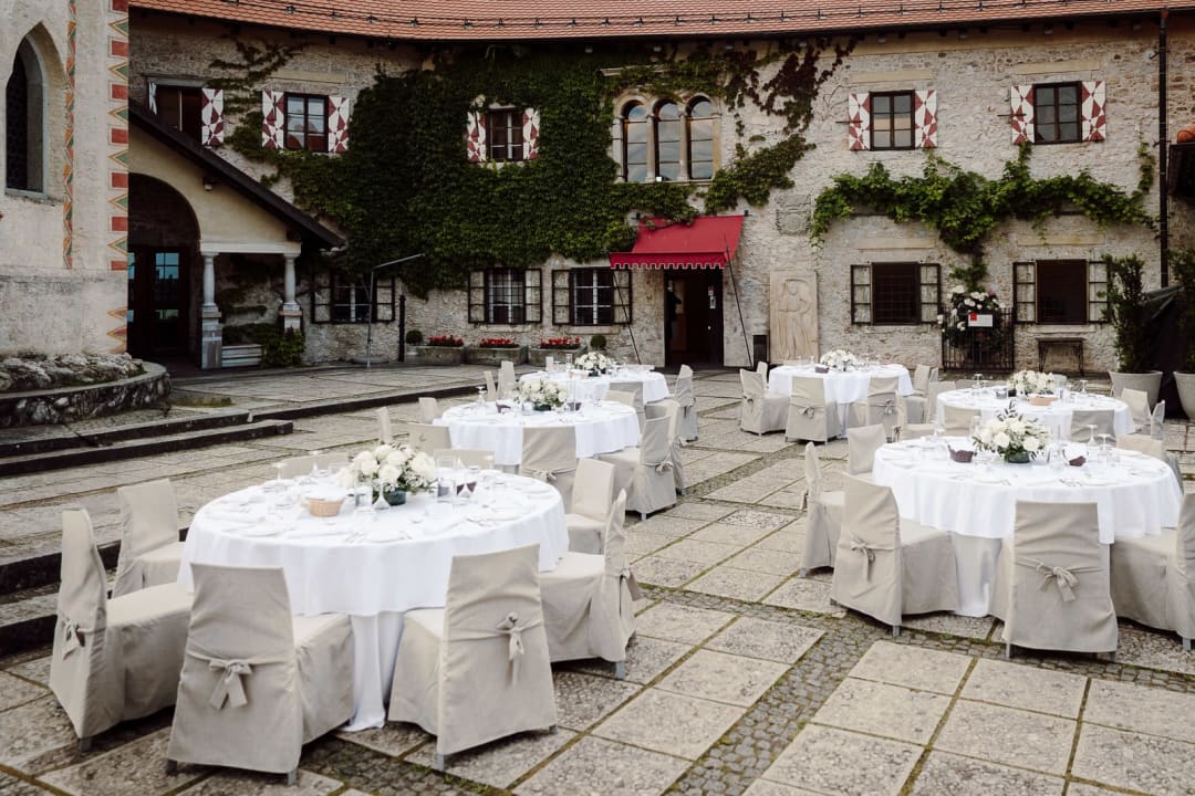Wedding reception tables set in the courtyard of Bled Castle with white linens and floral centerpieces, Lake Bled wedding.