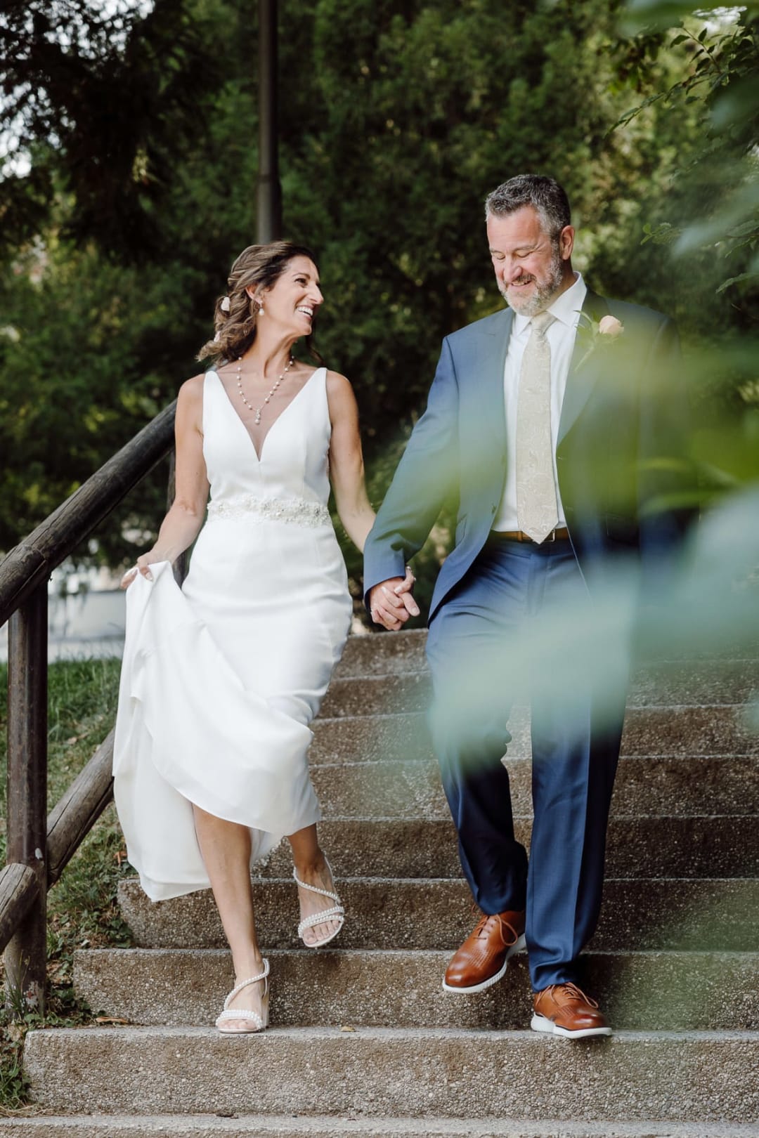 Bride and groom walking hand in hand through a quiet garden path.