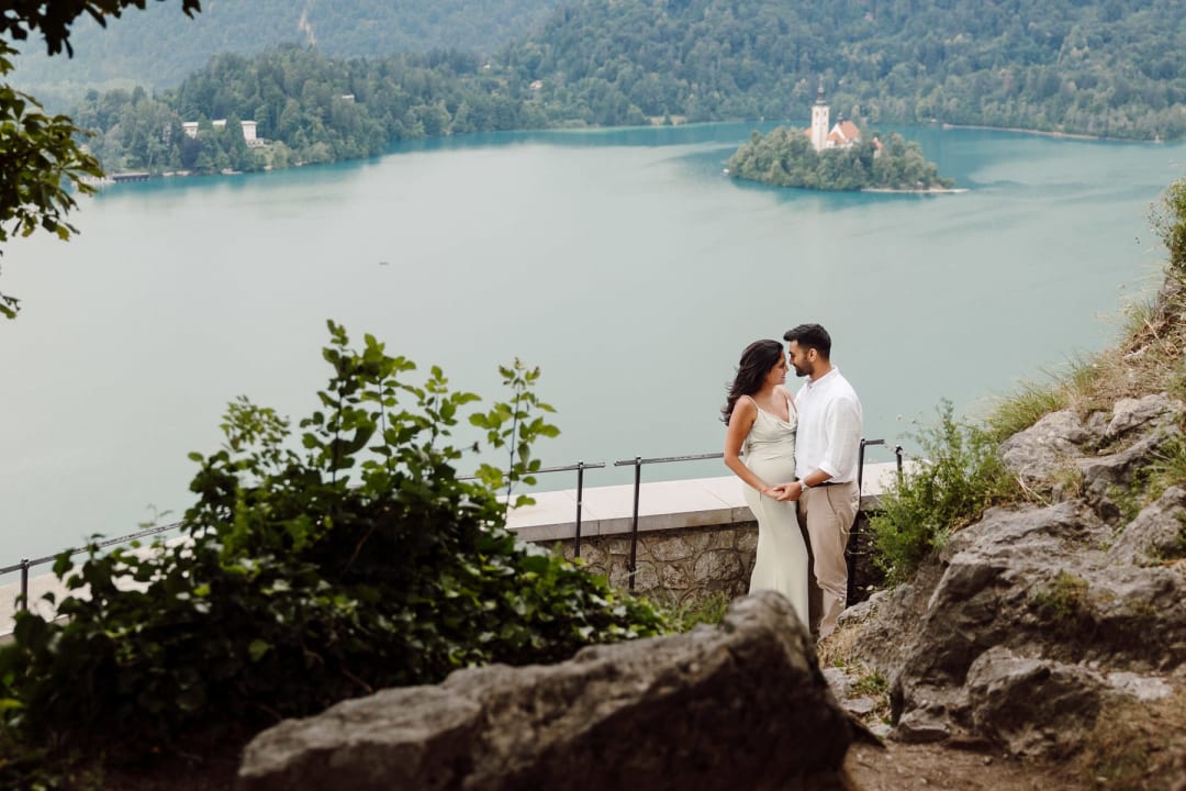 Romantic couple portrait at a Lake Bled viewpoint with the island behind them.