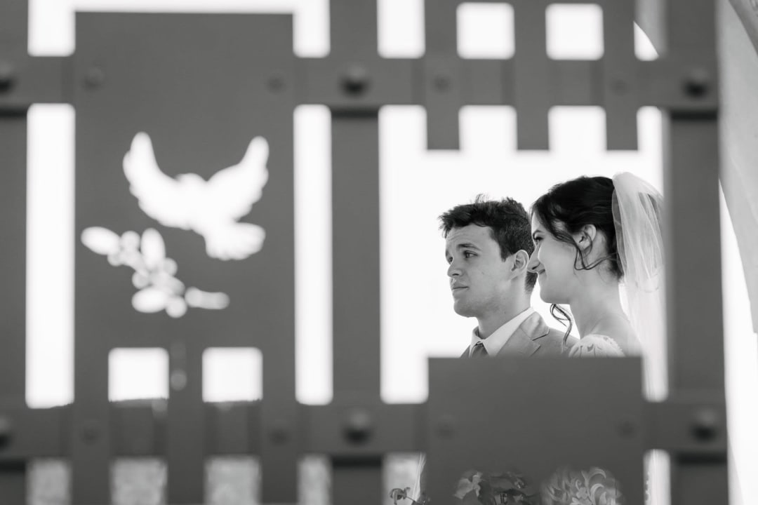 Artistic black and white ceremony shot framed through a decorative stone archway.