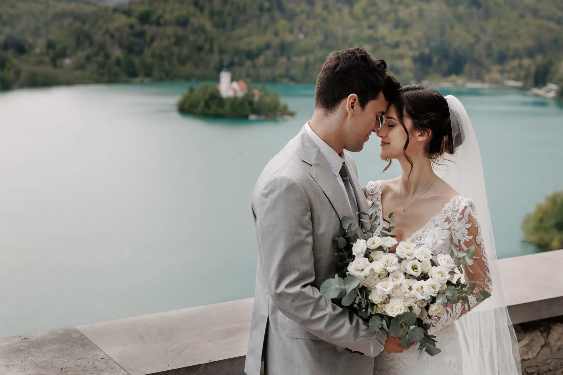 	Couple in a romantic embrace with the shimmering lake stretching out behind them.