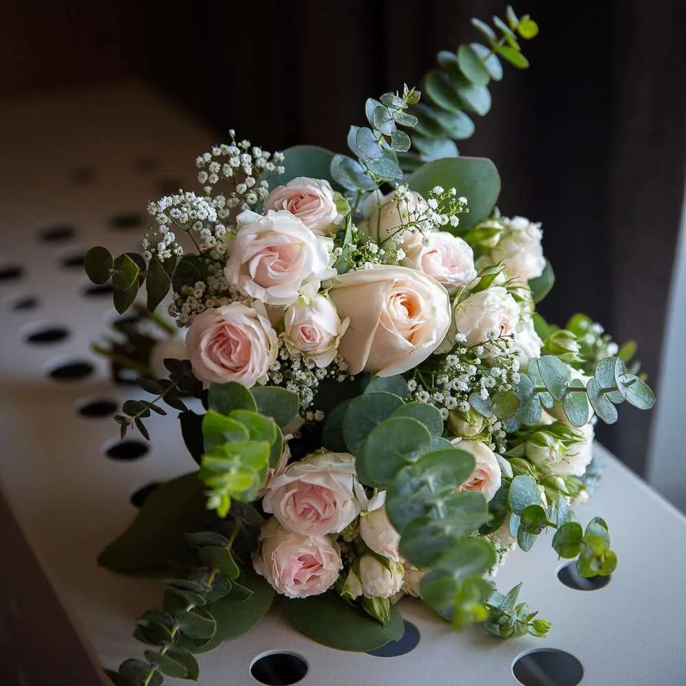 A beautifully arranged bridal bouquet featuring peach roses and eucalyptus leaves.