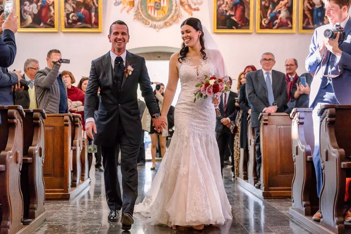 A bride and groom joyfully walking down the aisle in a church, surrounded by smiling guests.