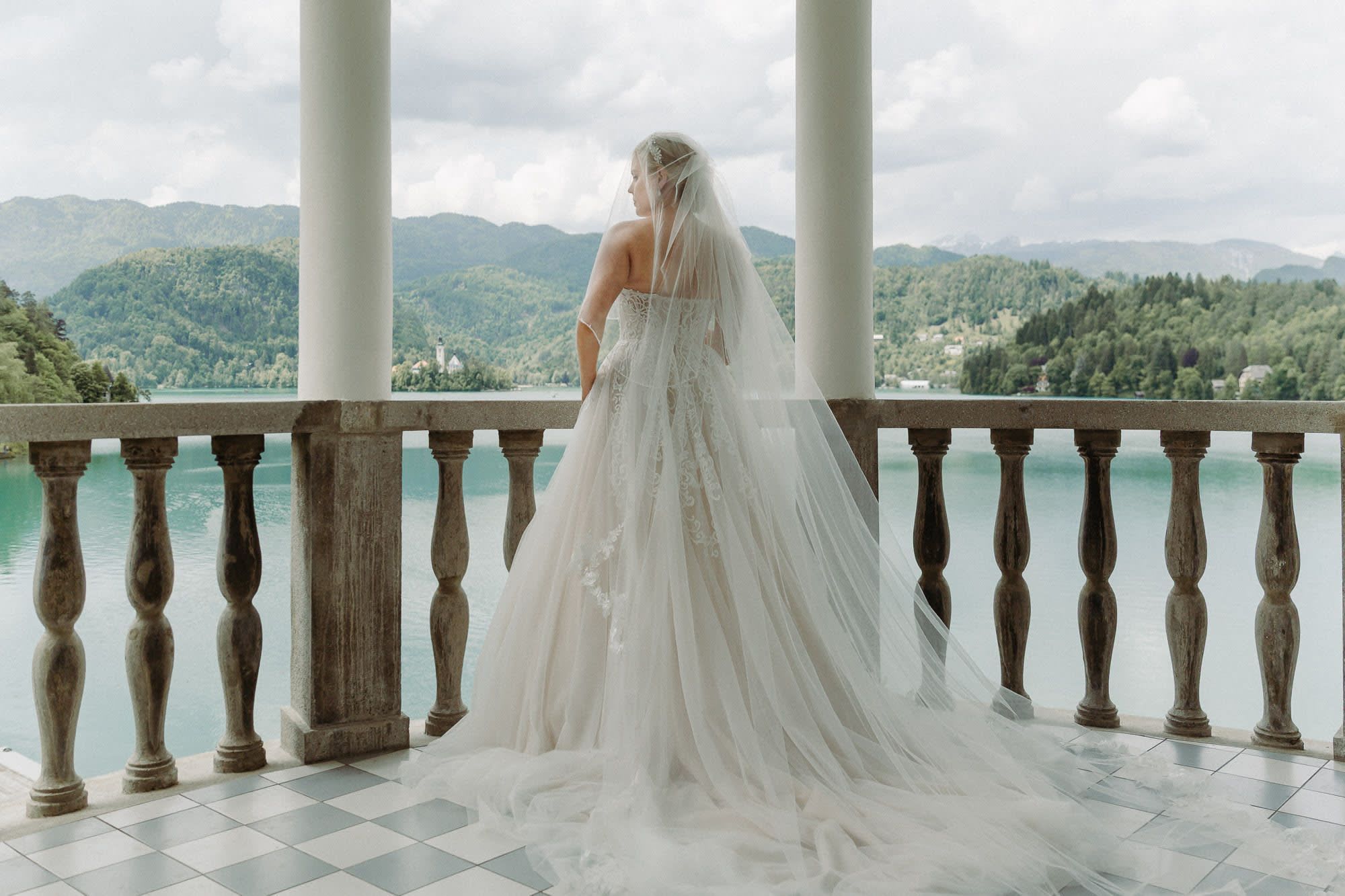 Bride portrait on the balcony of Grand Hotel Toplice overlooking Lake Bled and Bled Island, Slovenia.