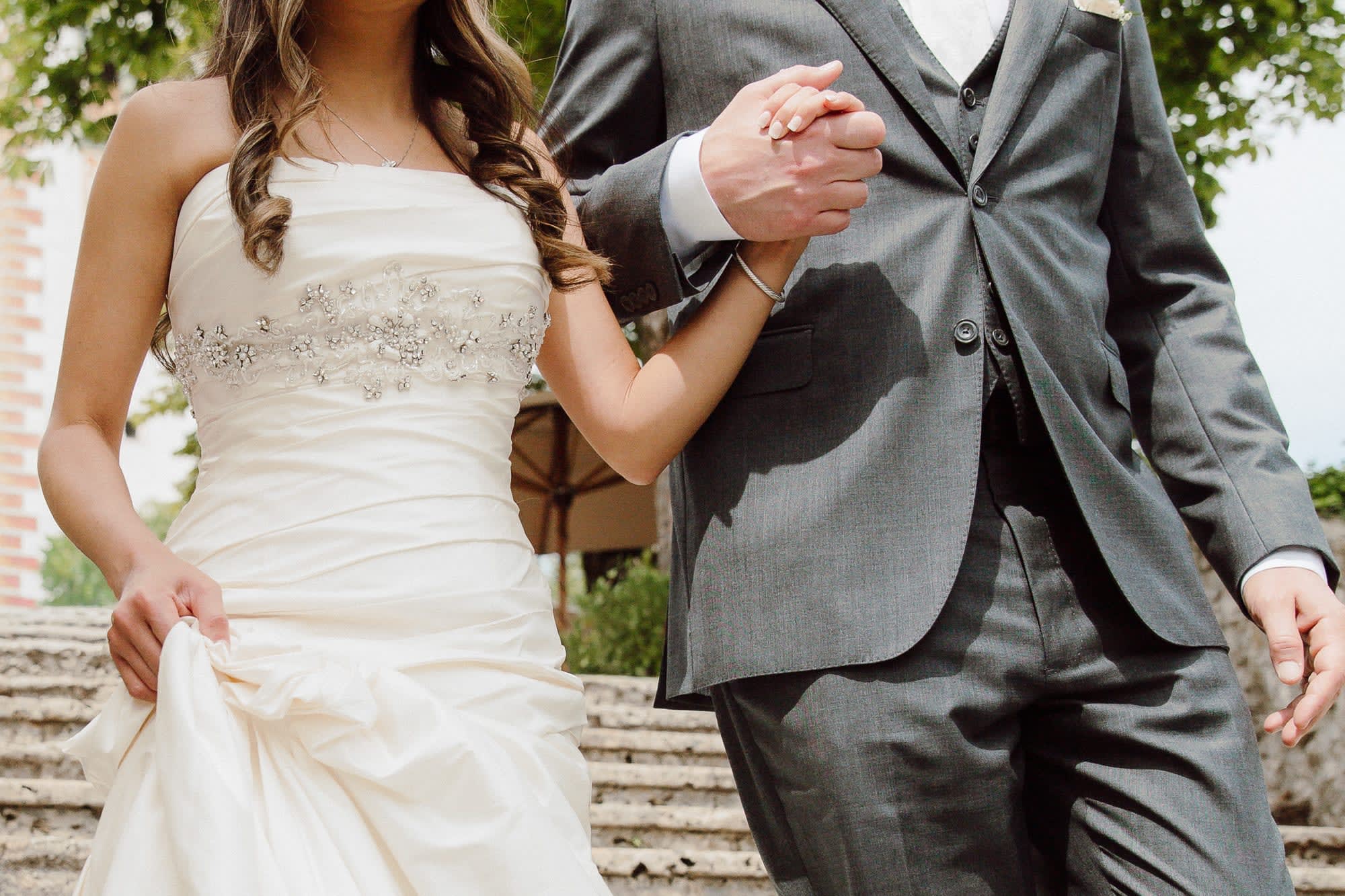 Close-up of a bride and groom holding hands while walking together during a quiet Lake Bled elopement.